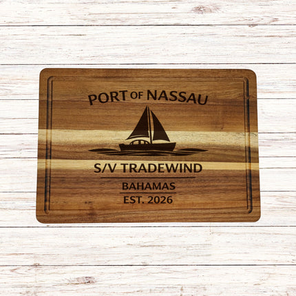 Wooden cutting board with engraved text and sailboat illustration on a wooden surface
