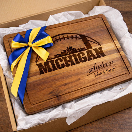 Personalized Michigan football cutting board presented as a gift with blue and maize ribbon