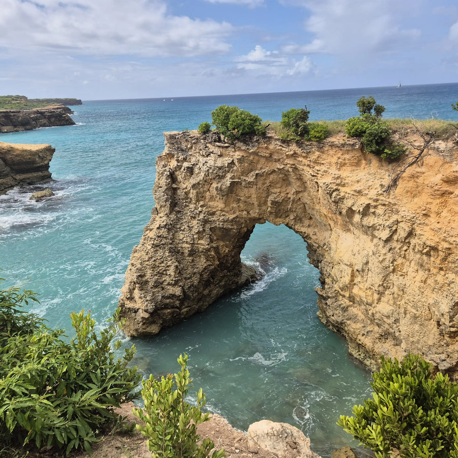 Natural limestone sea arch on the coast of Anguilla overlooking turquoise Caribbean waters and rugged shoreline cliffs