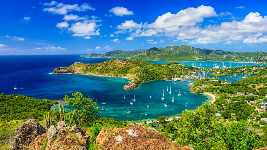 Panoramic aerial view of English Harbour and Nelson's Dockyard in Antigua & Barbuda, featuring protected anchorages, sailboats, and one of the Caribbean's premier cruising destinations.