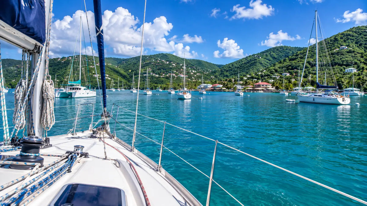 View from the cockpit of a cruising sailboat arriving in Coral Bay, St. John, U.S. Virgin Islands, with anchored sailboats, calm turquoise waters, and the peaceful waterfront ahead.