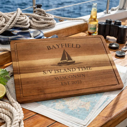 Personalized Bayfield cutting board displayed on sailboat deck with nautical gear representing Great Lakes sailing lifestyle