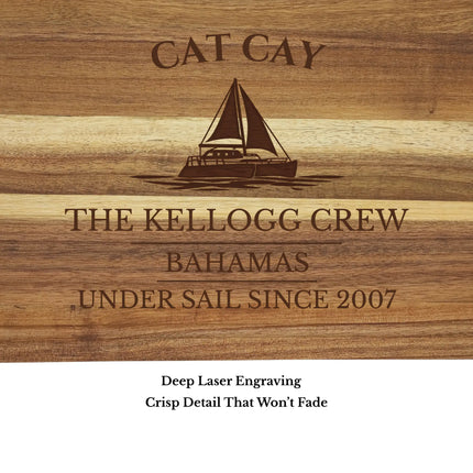 Close up of Cat Cay Bahamas sailboat cutting board engraving showing detailed sailboat design and acacia wood grain