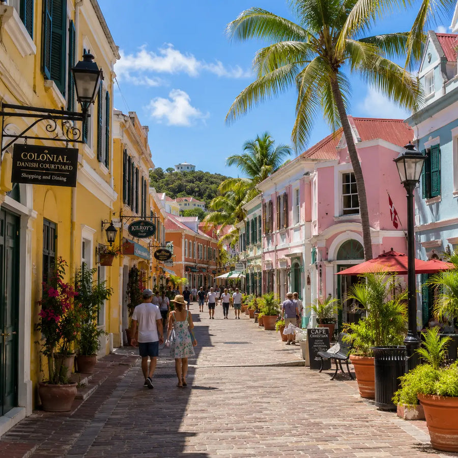 Colorful Danish colonial architecture in historic Christiansted, St. Croix, with palm-lined streets, cafés, shops, and pedestrians exploring one of the Caribbean's best-preserved colonial towns.