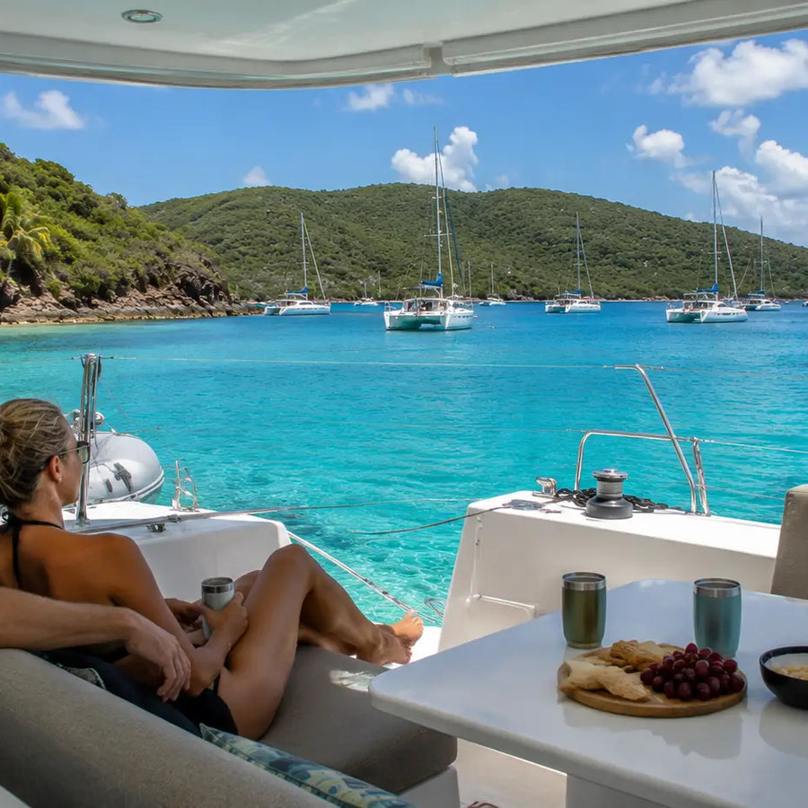 Cruisers relaxing aboard a catamaran anchored in Christmas Cove surrounded by the turquoise waters of the U.S. Virgin Islands.