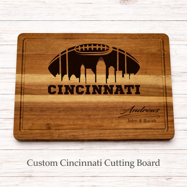 Custom Cincinnati football cutting board with skyline engraving and personalized family name, solid acacia wood on whitewashed background