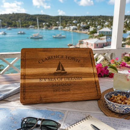 Clarence Town Bahamas sailboat cutting board displayed at a scenic harbor overlook with turquoise water anchored sailboats and tropical hillsides on Long Island