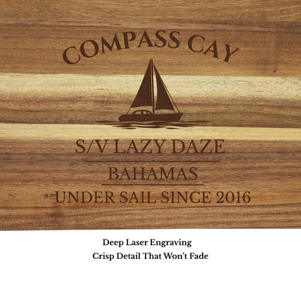 Close up of Compass Cay Bahamas sailboat cutting board engraving showing detailed sailboat design and acacia wood grain