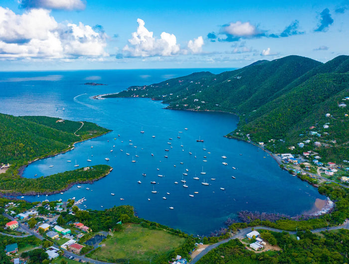 Aerial view of Coral Bay Harbor in St. John, U.S. Virgin Islands, showing the protected harbor, sailboats on moorings, lush tropical hills, and the quiet waterfront village.