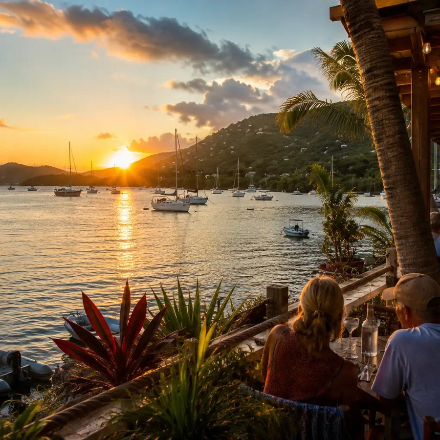 Outdoor waterfront dining overlooking Coral Bay Harbor at sunset in St. John, U.S. Virgin Islands, with anchored sailboats, tropical landscaping, and a relaxed Caribbean cruising atmosphere.