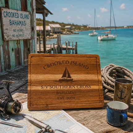 Crooked Island Bahamas sailboat cutting board displayed at a remote weathered dock beside calm turquoise water and rugged southern Bahamas coastline