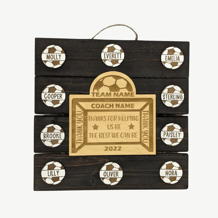 Wooden plaque with engraved names and soccer ball designs on a white background