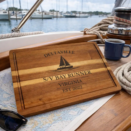 Deltaville Virginia personalized sailboat cutting board displayed on a sailboat chart table with marina view and nautical setting