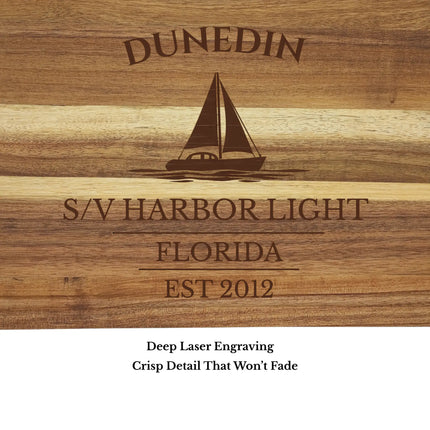 Close up of Dunedin Florida sailboat cutting board engraving showing detailed sailboat design and acacia wood grain