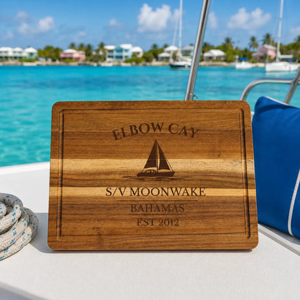 Elbow Cay Bahamas sailboat cutting board overlooking calm turquoise cruising water with colorful island cottages and anchored sailboats in the Abacos