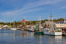 Coastal view of Fernandina Harbor featuring sailboats, marina docks, calm Intracoastal waters, palm trees, and historic waterfront buildings at golden hour along Florida’s northeastern coast.