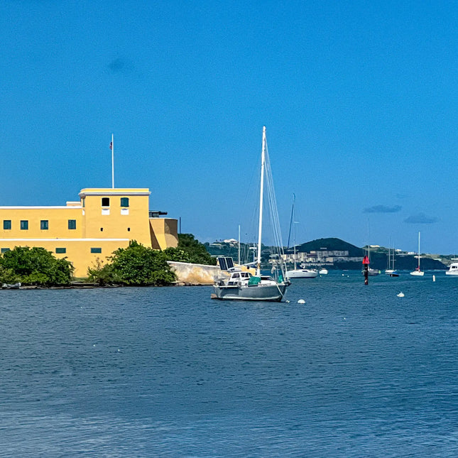 Historic Fort Christiansvaern overlooking Christiansted Harbor on St. Croix, U.S. Virgin Islands, with a sailboat anchored in the protected harbor.
