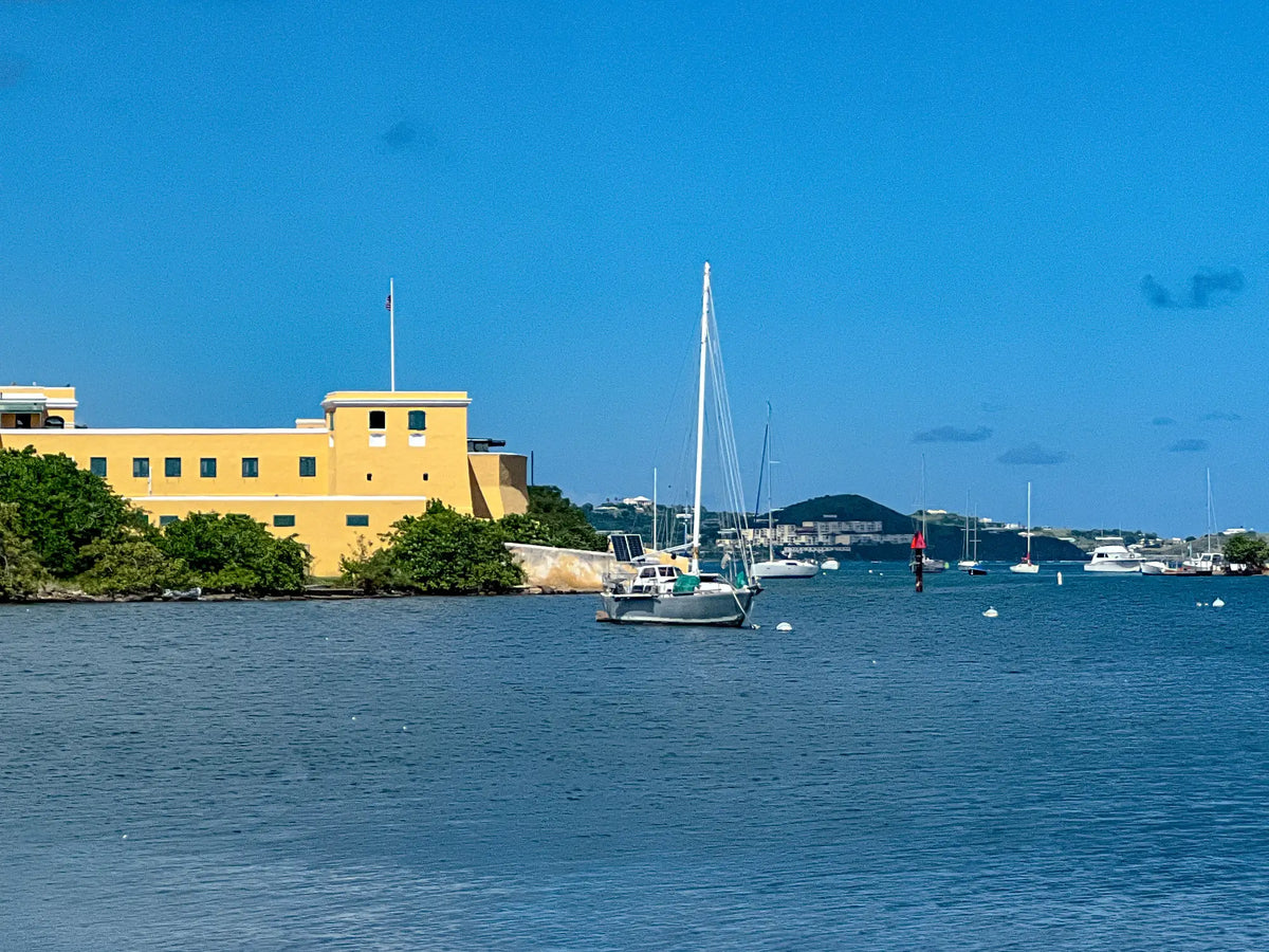Historic Fort Christiansvaern overlooking Christiansted Harbor on St. Croix, U.S. Virgin Islands, with a sailboat anchored in the protected harbor.