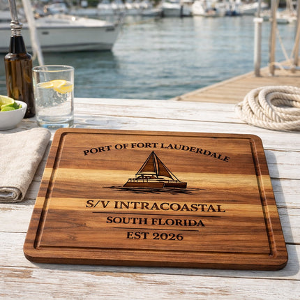 Personalized Fort Lauderdale sailboat cutting board displayed on a dockside table near a marina, engraved with boat name, home port, and year, showing use as a galley or coastal kitchen serving board