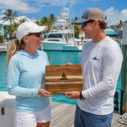 Freeport Bahamas personalized cutting board being exchanged as a gift at a tropical marina with turquoise water and sportfishing boats nearby