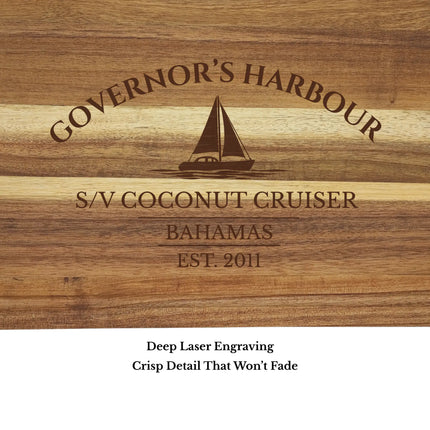 Close up of Governor’s Harbour Bahamas sailboat cutting board engraving showing detailed sailboat design and acacia wood grain