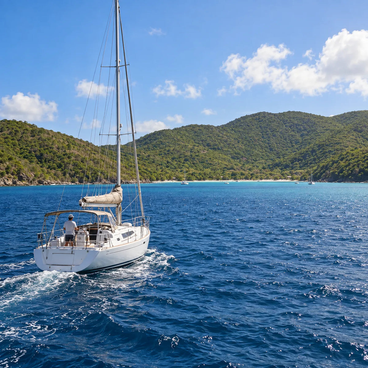 Sailboat underway on blue water toward a green, hilly shoreline, with several boats in the distant bay.