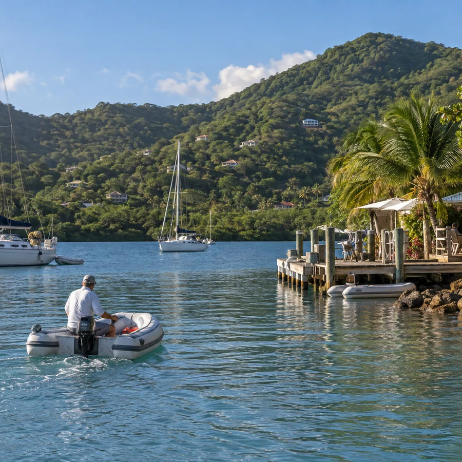 Cruiser operating a dinghy near anchored sailboats and a tropical waterfront at Soper’s Hole.