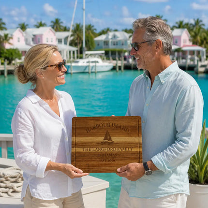 Harbour Island Bahamas personalized cutting board being exchanged as a gift near a waterfront harbor patio with turquoise water and pastel island cottages