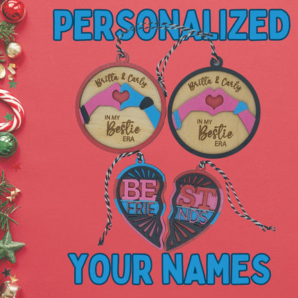Festive holiday display of personalized wooden best friend ornaments on a red background. Two round ornaments read “Britta & Carly – In My Bestie Era,” and a colorful split heart ornament spells “Best Friends.” The left side of the image is decorated with pine branches, candy canes, red and green ornaments, and glittery stars. Blue text above and below the ornaments reads “PERSONALIZED YOUR NAMES.”
