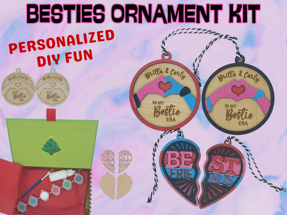 A colorful product display for a “Besties Ornament Kit.” The image shows wooden ornaments in round and heart shapes, some unfinished and others painted in pink, blue, and red with engraved text like “Britta & Carly – In My Bestie Era” and “Best Friends.” A green holiday box contains paint pots, a brush, glue, and twine for hanging. The background is pastel pink and blue with bold text reading “BESTIES ORNAMENT KIT” and “PERSONALIZED DIY FUN.”