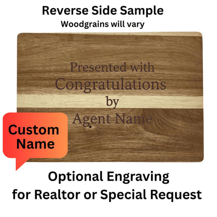 Image showing the back side of a personalized acacia wood cutting board with engraving that reads, “Presented with Congratulations by Agent Name.” A red speech bubble highlights “Custom Name.” Text above and below explains: “Reverse Side Sample – Woodgrains will vary” and “Optional Engraving for Realtor or Special Request.”