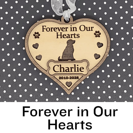 Heart-shaped wooden dog memorial ornament engraved with “Forever in Our Hearts,” featuring a dog silhouette, paw prints, and hearts. The ornament includes the name “Charlie” and dates “2010–2025,” with a white ribbon for hanging, displayed against a black background with white polka dots. Text below reads “Forever in Our Hearts.”