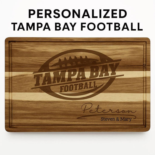 Personalized acacia wood cutting board engraved with a football logo and the text “Tampa Bay Football,” along with the family name “Peterson” and “Steven & Mary” in script at the bottom right. The board features natural striped wood grain and a carved juice groove, displayed against a white background with the words “PERSONALIZED TAMPA BAY FOOTBALL” above it.