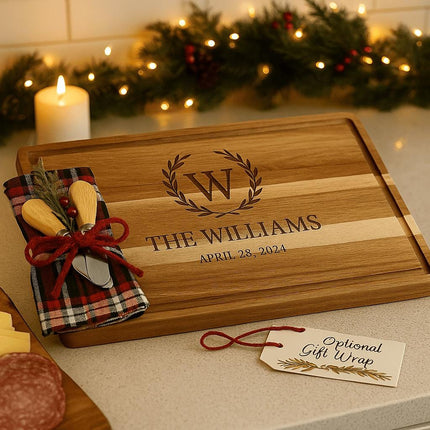 "Personalized acacia cutting board gift set with holiday plaid towel and two cheese spreaders, engraved with the family name and established date. Displayed on a neutral background with decorative greenery, showing components included in the gift set."