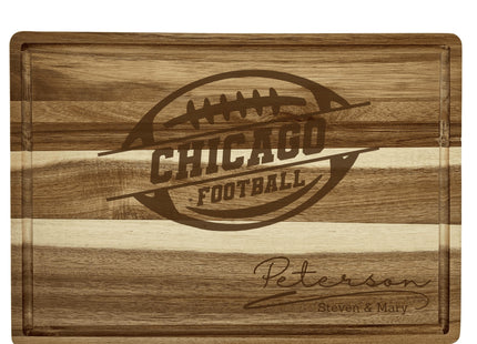 “Personalized Chicago football cutting board crafted from acacia wood with alternating light and dark woodgrain stripes. Engraved with a football logo and the family name ‘Peterson – Steven & Mary.’ Features a juice groove border, showcasing a rich natural finish and engraved design perfect for football fans or gift giving.”