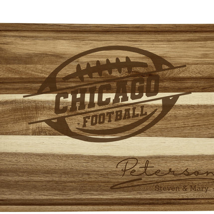 “Personalized Chicago football cutting board crafted from acacia wood with alternating light and dark woodgrain stripes. Engraved with a football logo and the family name ‘Peterson – Steven & Mary.’ Features a juice groove border, showcasing a rich natural finish and engraved design perfect for football fans or gift giving.”