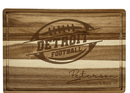 “Personalized Detroit football cutting board crafted from acacia wood with light and dark striped grain. Engraved with a football logo and the family name ‘Peterson – Steven & Mary.’ Features a juice groove border and smooth finish, highlighting its quality craftsmanship and suitability as a gift for football fans.”