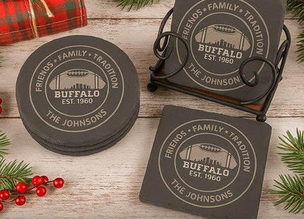 &quot;Festive holiday scene featuring a set of four personalized Buffalo-themed slate drink coasters, available in round and square shapes. Each coaster is engraved with the text &#39;Friends • Family • Tradition,&#39; &#39;Buffalo Est. 1960,&#39; and &#39;The Johnsons.&#39; The set is displayed with an optional black iron coaster holder, surrounded by pine branches, red berries, and a red plaid napkin on a rustic wooden surface. Text overlay reads: &#39;Set of 4 Custom Buffalo Drink Coasters –