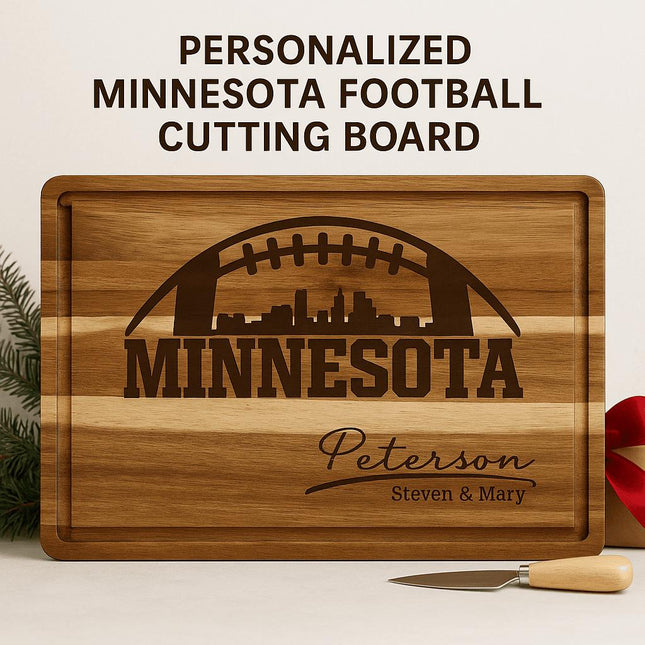 "Personalized Minnesota football cutting board made of striped acacia wood with engraved football and city skyline design. The engraving reads 'MINNESOTA' with the family name 'Peterson' and 'Steven & Mary' below. Displayed with a small cheese knife and red ribbon, set against a clean neutral background with evergreen accents."