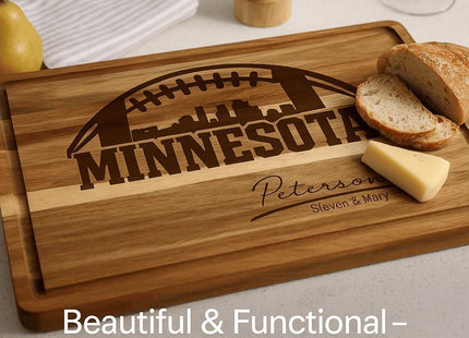 &quot;Personalized Minnesota football cutting board made of acacia wood, engraved with a football and skyline design and the name &#39;Peterson – Steven & Mary.&#39; The board is shown on a kitchen counter with sliced bread, a wedge of cheese, and a pear nearby. Text overlay reads &#39;Beautiful & Functional – Everyday Use.&#39;&quot;