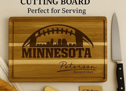 &quot;Personalized Minnesota football cutting board made of acacia wood, engraved with a football and skyline design and the name &#39;Peterson – Steven & Mary.&#39; The board measures 15.75 by 11 inches and is shown with bread, a large knife, and two small cheese spreaders. A gift tag reads &#39;Gift Box Optional.&#39; Text overlay reads &#39;Large 15.75&quot; × 11&quot; Cutting Board – Perfect for Serving.&#39;&quot;