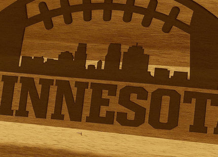 &quot;Close-up view of a laser-engraved Minnesota football design on an acacia wood cutting board, featuring a football outline with a city skyline and the word &#39;MINNESOTA&#39; engraved below.&quot;