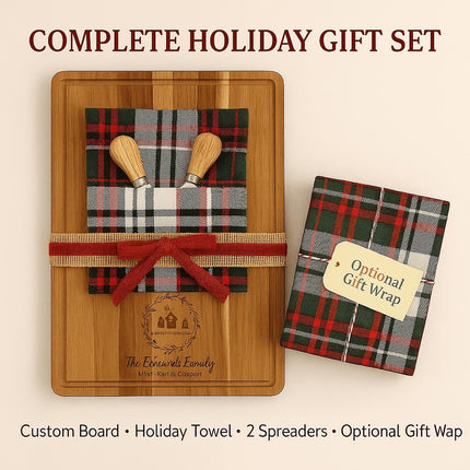 : Personalized acacia cutting board holiday gift set displayed with a plaid holiday towel, two wooden spreader knives, and a red ribbon bow wrapped around the board. Next to it is a matching plaid gift-wrapped box with a tag that reads “Optional Gift Wrap.” The engraving on the board shows a family name and holiday design. Text above reads “COMPLETE HOLIDAY GIFT SET,” and below lists the contents: “Custom Board • Holiday Towel • 2 Spreaders • Optional Gift Wrap.”