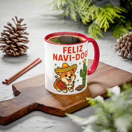 "Festive red-handled mug filled with coffee, featuring a cute cartoon corgi wearing a sombrero and poncho next to a cactus and the text 'Feliz Navi-Dog!' The mug sits on a wooden cutting board surrounded by pinecones, cinnamon sticks, and holiday greenery, creating a cozy Christmas atmosphere."