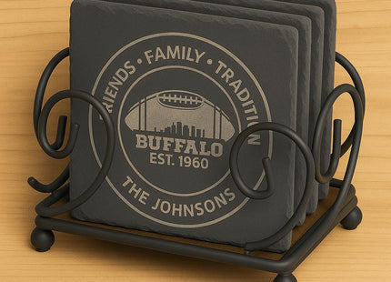 &quot;Set of four square black slate coasters engraved with a Buffalo football design displayed in a black wrought iron holder. The coasters feature the text &#39;Friends • Family • Tradition,&#39; &#39;Buffalo Est. 1960,&#39; and &#39;The Johnsons.&#39; The holder has decorative scrollwork and sits on a light wooden surface.&quot;