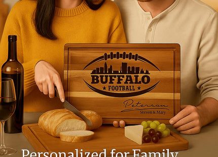 &quot;Smiling couple enjoying wine and cheese while using a personalized Buffalo Football cutting board engraved with a football and skyline design and the name &#39;Peterson.&#39; The board is displayed with bread, cheese, and grapes on a dining table. Text reads &#39;Personalized for Family Moments & Game-Day Traditions,&#39; emphasizing warmth and togetherness.&quot;