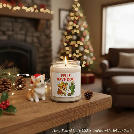 "Festive holiday scene featuring a lit 'Feliz Navi-Dog!' candle on a wooden mantle beside a small Corgi figurine wearing a Santa hat. The background shows a decorated Christmas tree with glowing lights, a cozy stone fireplace, and holiday greenery with pinecones and holly. Text at the bottom reads 'Hand-Poured in the USA • Crafted with Holiday Spirit.'"