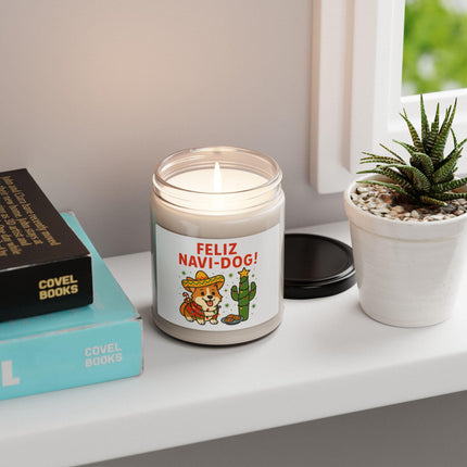 "Lit 'Feliz Navi-Dog!' holiday candle with a festive Corgi wearing a sombrero and cactus design placed on a white windowsill. The candle sits beside a small potted succulent and a stack of books, creating a cozy and minimal home decor scene with natural daylight coming through the window."
