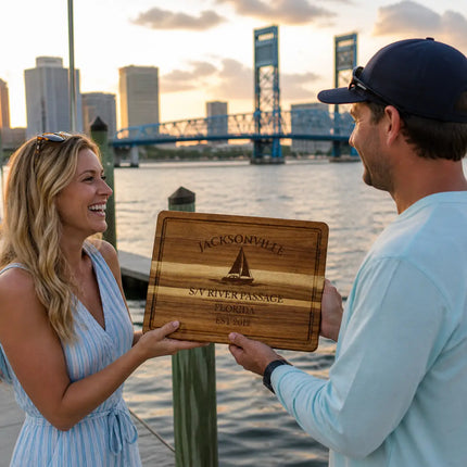 Jacksonville Florida personalized cutting board being given as a gift on a dock at sunset with river water bridge and marina background
