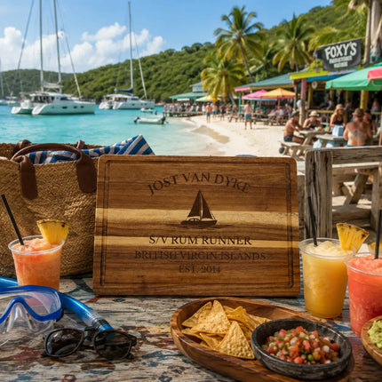 Jost Van Dyke British Virgin Islands sailboat cutting board displayed beside turquoise Caribbean water beach bars catamarans palm trees and tropical island scenery